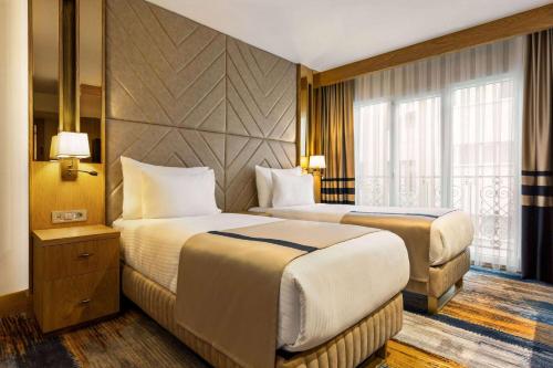 伊斯坦布尔Days Inn by Wyndham Istanbul Bomonti的酒店客房设有两张床和窗户。