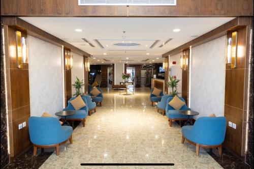 吉达Sweet Home For Serviced Accommodation的酒店大堂的走廊,设有蓝色的椅子和桌子