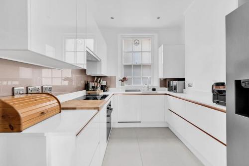 伦敦Luxury 3 bedroom apartment in the heart of High Street Kensington, London.的白色的厨房配有白色的橱柜和木台面