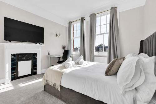 伦敦Luxury 3 bedroom apartment in the heart of High Street Kensington, London.的白色卧室设有一张大床和一台平面电视。