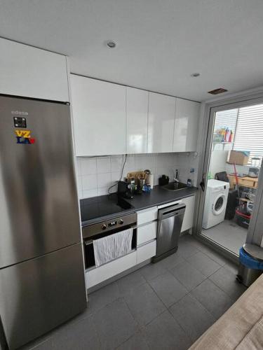 马德里Cómodo apartamento en Madrid的厨房配有白色橱柜和不锈钢冰箱