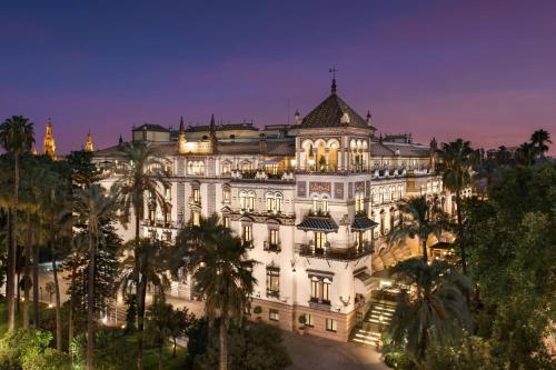 塞维利亚Hotel Alfonso XIII, a Luxury Collection Hotel, Seville的一座白色的大建筑,晚上种有棕榈树