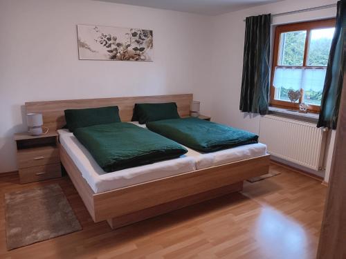 拉姆Ferienwohnung Butterfly的一间卧室配有一张带绿色床单的床和一扇窗户。