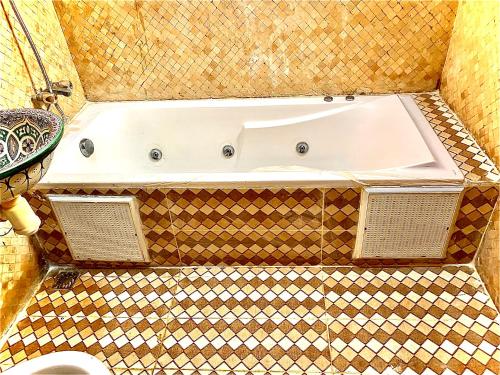 马拉喀什Riad Nezha的带浴缸的浴室,铺有瓷砖地板