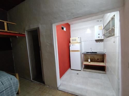 福尔摩沙Departamento Planta Baja. Centro. Pileta的一间小厨房,配有白色冰箱和红色的墙壁