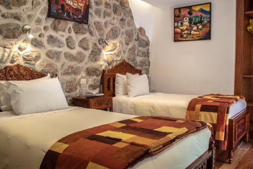 库斯科阿马鲁印加宾馆的一间设有两张床和石墙的房间