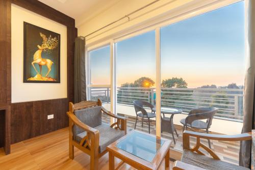 达兰萨拉Stone Wood Mountain Resort, Dharamshala的客厅配有桌椅和大窗户
