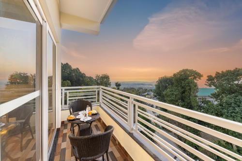 达兰萨拉Stone Wood Mountain Resort, Dharamshala的设有一个配有桌椅并享有美景的阳台。