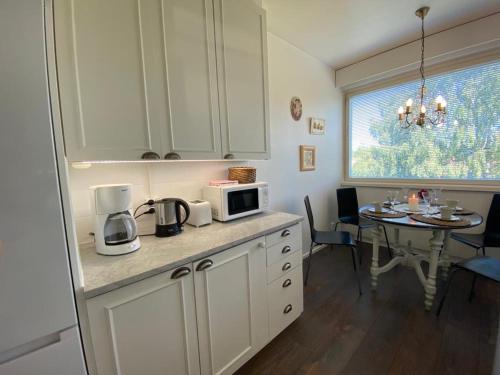 凯米Style 1BR Appartment in Kemi - Tornio的厨房配有白色橱柜和带微波炉的桌子。