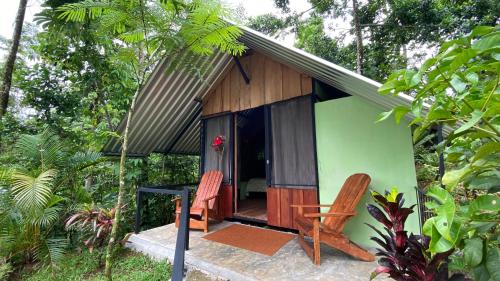 TigraGuapote Lodge的一座带两把椅子的绿色木屋