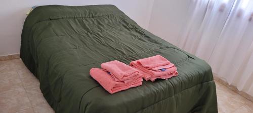 圣胡利安港ALOJAMIENTOS BJ的绿色的床,上面有两条粉红色的毛巾