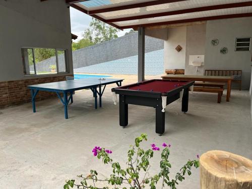 迈里波朗Chácara em Alpes de Mairiporã的天井设有2张乒乓球桌和1张长凳