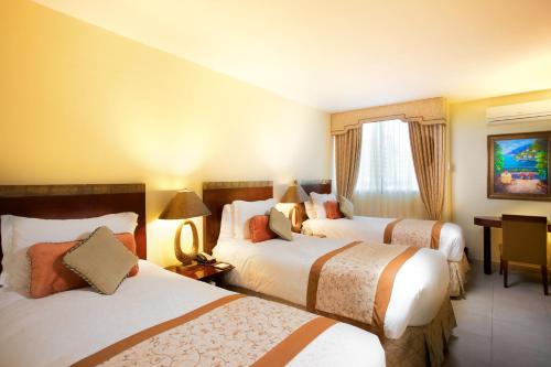 巴拿马城TOSCANA INN HOTEL的酒店客房设有三张床和一张书桌