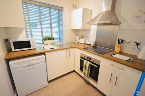 考文垂Remarkable 3-Bed Ground Floor Apartment - Coventry的厨房配有白色橱柜和炉灶烤箱。