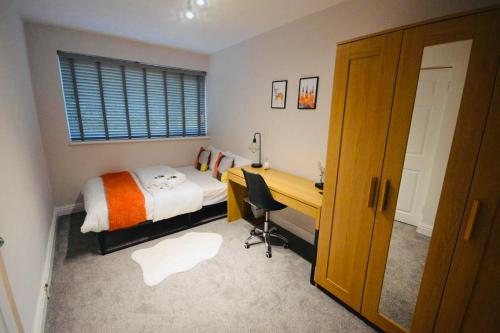 考文垂Remarkable 3-Bed Ground Floor Apartment - Coventry的一间卧室配有一张床、一张书桌和一个窗户。