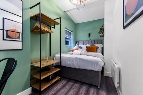 伦敦Fabulous One Bedroom Flat with Private Garden的一间卧室设有绿色的墙壁和一张带橙色枕头的床