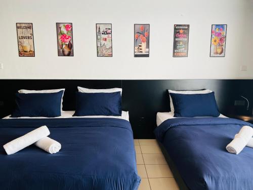 丹绒亚路M Suite Homestay, Aeropod Sovo Kota Kinabalu的配有两张蓝色和白色床单的床铺