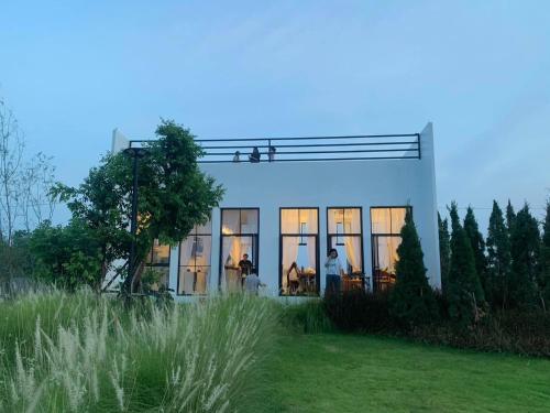 Ban Wang Dinริมยมรีสอร์ท的草坪上带玻璃窗的白色房屋