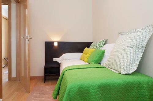 维多利亚-加斯特伊兹怡和阿里斯蒂公寓式酒店的一张带绿色和黄色枕头的床