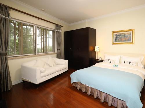 上海国际丽都公馆的一间卧室配有一张大床和一张白色沙发