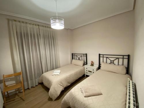卡拉瓦卡·德·拉·克鲁斯Apartamentos Plaza del Arco的一间卧室配有两张床和吊灯。