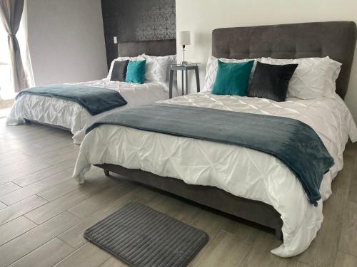 San Mateo XolocHotel Del Real的一间卧室配有两张带绿色和白色床单的床