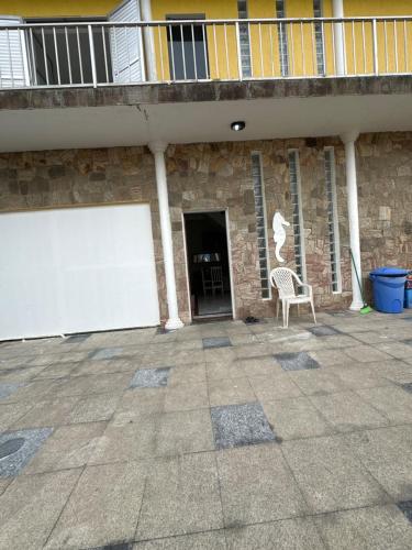 蒙加瓜Hostel Encanto de Mongaguá的一座带白色车库门和椅子的建筑