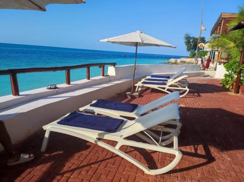 南威Blue Tides Hotel的俯瞰大海的阳台配有2把躺椅和1把遮阳伞