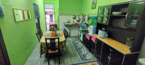 Kampung GurunHomestay D'Murni的厨房设有绿色的墙壁、桌子和柜台