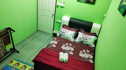 Kampung GurunHomestay D'Murni的绿色卧室配有带拖鞋的床