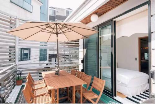 首尔汉所总统套房韩屋酒店的阳台上配有一张木桌和椅子及遮阳伞