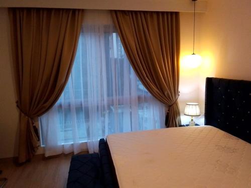 阿克拉1 BDR 74SQM Luxury APT with separate Bedroom Pool, Gym, Balcony, King Size Bed Cantonments的一间卧室配有床和带窗帘的窗户