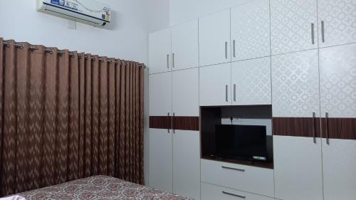 德里久尔Niks home stay - A的一间带电视和白色橱柜的卧室