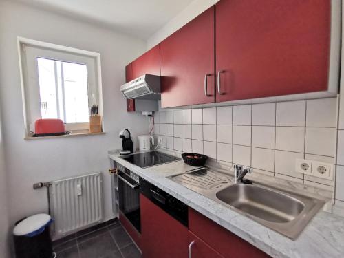 巴特克罗伊茨纳赫Komfortable 2-Zimmer-Ferienwohnung am Kurpark的一间带红色橱柜和水槽的厨房
