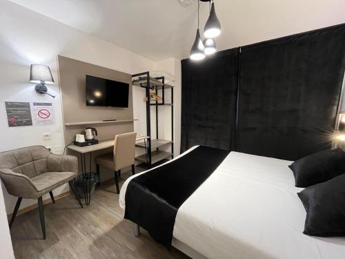 科涅克Cit'Hotel Le Cheval Blanc Cognac Centre的一间卧室配有一张床、一张书桌和一台电视