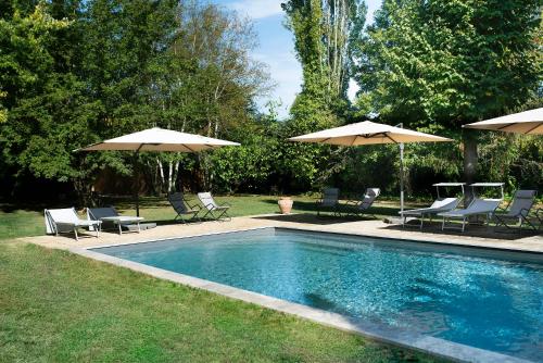 菲利内瓦尔达诺Casale La Gora - B&B di charme的游泳池配有两把遮阳伞和椅子以及四柱四柱床