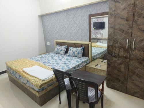 PratāpgarhHotel Divine and Restaurant的小房间设有一张床、一张桌子和椅子