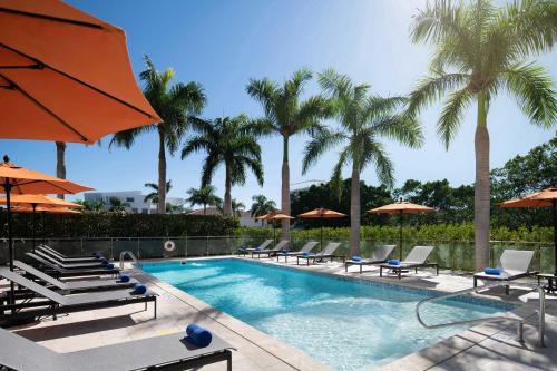 蓬塔卡纳福朋喜来登蓬塔卡纳村酒店的一个带椅子和遮阳伞的游泳池以及棕榈树