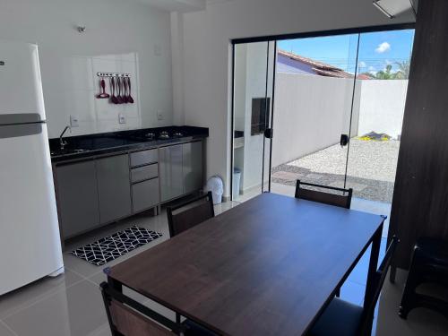 南圣弗朗西斯科Brisas de São Chico - 450m da Praia的厨房配有木桌和大型滑动玻璃门。