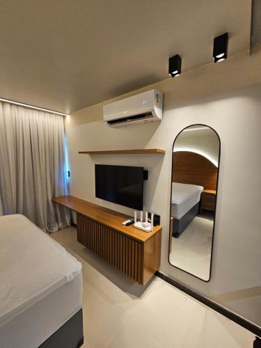 塔曼达雷Praia dos Carneiros flat hotel的一间带镜子、一张床和电视的卧室