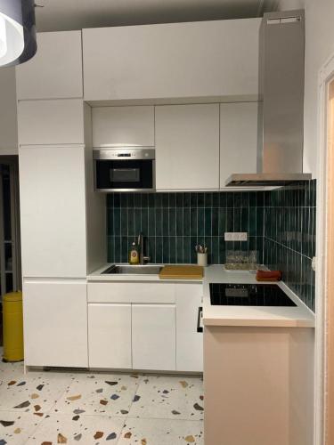尼姆La Halte des Arènes de Nîmes Appartement de charme Terracotta的厨房配有白色橱柜和炉灶烤箱。