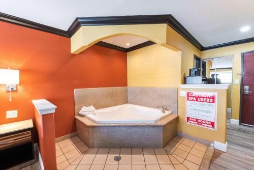 萨克拉门托Quality Inn & Suites的浴缸位于带橙色墙壁的房间内