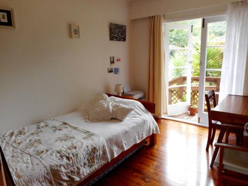 TuamarinaSunrise Beach House - Rarangi Holiday House的一间卧室设有一张床和一个滑动玻璃门