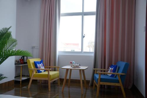 梅州湄洲岛悦榕湾民宿的一间设有两把椅子、一张桌子和一个窗户的房间