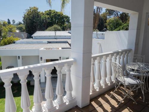 比勒陀利亚Kelkiewyn Waterkloof Guesthouse的阳台上的白色栏杆和椅子