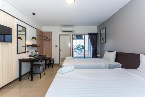 曼谷CK2 Hotel SHA EXTRA PLUS的酒店客房配有两张床和一张书桌
