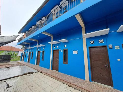 占碑市SPOT ON 93465 Archa Guest House Syariah的蓝色的建筑,有棕色的门