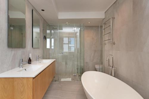 开普敦The Cosmo Luxury Suites by Totalstay的浴室配有2个盥洗盆、浴缸和淋浴。