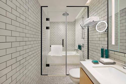 深圳深圳机场希尔顿逸林公寓的带浴缸、卫生间和盥洗盆的浴室