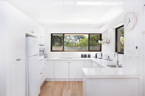 穆卢拉巴Windmill 3的白色的厨房配有白色橱柜和窗户